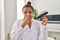 Young hispanic dentist woman holding teeth whitening samples covering mouth with hand, shocked and afraid for mistake Royalty Free Stock Photo