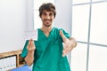 Young hispanic doctor man holding covid record card smiling friendly offering handshake as greeting and welcoming Royalty Free Stock Photo