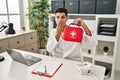 Young hispanic doctor man holding first aid kit covering mouth with hand, shocked and afraid for mistake Royalty Free Stock Photo