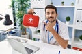 Young hispanic doctor man holding first aid kit smiling happy pointing with hand and finger Royalty Free Stock Photo