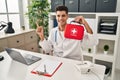 Young hispanic doctor man holding first aid kit smiling happy pointing with hand and finger to the side Royalty Free Stock Photo