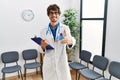 Young hispanic doctor man at waiting room smiling friendly offering handshake as greeting and welcoming Royalty Free Stock Photo