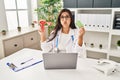 Young hispanic doctor woman holding anatomical female genital organ and birth control pills puffing cheeks with funny face Royalty Free Stock Photo