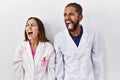 Young hispanic doctors standing over white background angry and mad screaming frustrated and furious, shouting with anger