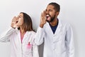 Young hispanic doctors standing over white background shouting and screaming loud to side with hand on mouth