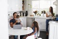 Young Hispanic family in their kitchen, dad holding baby, mum cooking at the hob Royalty Free Stock Photo