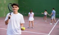 Young hispanic frontenis player on open-air fronton court with racket and balls