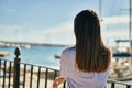 Young hispanic girl on back view leaning on the balustrad at the port