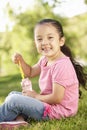 Young Hispanic Girl Blowing Bubbles In Park