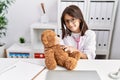 Young hispanic girl checking teddy bear health at doctor clinic Royalty Free Stock Photo