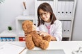 Young hispanic girl checking teddy bear health at doctor clinic Royalty Free Stock Photo