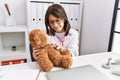 Young hispanic girl checking teddy bear health at doctor clinic Royalty Free Stock Photo