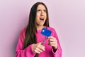 Young hispanic girl cutting credit card using scissors angry and mad screaming frustrated and furious, shouting with anger looking Royalty Free Stock Photo