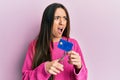 Young hispanic girl cutting credit card using scissors angry and mad screaming frustrated and furious, shouting with anger Royalty Free Stock Photo