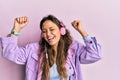 Young hispanic girl dancing and listening to music using headphones smiling and laughing hard out loud because funny crazy joke Royalty Free Stock Photo