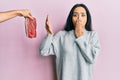 Young hispanic girl on diet rejecting beef covering mouth with hand, shocked and afraid for mistake Royalty Free Stock Photo