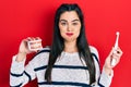 Young hispanic girl holding electric toothbrush and denture puffing cheeks with funny face Royalty Free Stock Photo