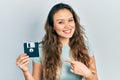 Young hispanic girl holding floppy disk smiling happy pointing with hand and finger Royalty Free Stock Photo