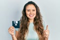 Young hispanic girl holding floppy disk smiling with an idea or question pointing finger with happy face, number one Royalty Free Stock Photo