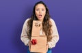Young hispanic girl holding gifts afraid and shocked with surprise and amazed expression, fear and excited face Royalty Free Stock Photo