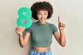 Young hispanic girl holding number eight smiling with an idea or question pointing finger with happy face, number one Royalty Free Stock Photo