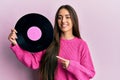 Young hispanic girl holding vinyl disc smiling happy pointing with hand and finger Royalty Free Stock Photo