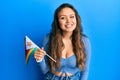 Young hispanic girl holding zimbabwe flag looking positive and happy standing and smiling with a confident smile showing teeth Royalty Free Stock Photo