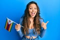 Young hispanic girl holding zimbabwe flag pointing thumb up to the side smiling happy with open mouth Royalty Free Stock Photo