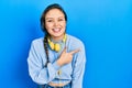 Young hispanic girl listening to music using headphones smiling cheerful pointing with hand and finger up to the side Royalty Free Stock Photo