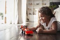 Young Hispanic girl lying on the floor in the sitting room playing with a toy digger truck Royalty Free Stock Photo