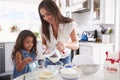 Young Hispanic girl making cake in the kitchen with help from her mum, waist up Royalty Free Stock Photo