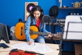 Young hispanic girl musician composing song playing classical guitar at music studio Royalty Free Stock Photo