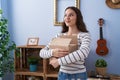 Young hispanic girl opening cardboard box smiling looking to the side and staring away thinking Royalty Free Stock Photo