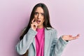 Young hispanic girl presenting with open palms, holding something in shock face, looking skeptical and sarcastic, surprised with Royalty Free Stock Photo