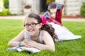 Young Hispanic Girl Reading Outside Smiling