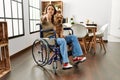 Young hispanic girl sitting on wheelchair at home smiling friendly offering handshake as greeting and welcoming Royalty Free Stock Photo