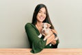 Young hispanic girl smiling happy and hugging dog sitting on the table over isolated white background Royalty Free Stock Photo