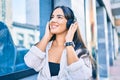 Young hispanic girl smiling happy listening to music using headphones at the city Royalty Free Stock Photo