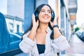 Young hispanic girl smiling happy listening to music using headphones at the city Royalty Free Stock Photo