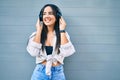 Young hispanic girl smiling happy listening to music using headphones at the city Royalty Free Stock Photo