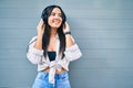 Young hispanic girl smiling happy listening to music using headphones at the city Royalty Free Stock Photo