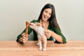 Young hispanic girl smiling happy and playing with dog sitting on the table over isolated white background Royalty Free Stock Photo