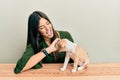 Young hispanic girl smiling happy and playing with dog sitting on the table over isolated white background Royalty Free Stock Photo