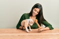 Young hispanic girl smiling happy and playing with dog sitting on the table over isolated white background Royalty Free Stock Photo