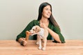 Young hispanic girl smiling happy and playing with dog sitting on the table over isolated white background Royalty Free Stock Photo