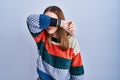 Young hispanic girl standing over blue background covering eyes with arm, looking serious and sad Royalty Free Stock Photo