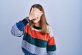 Young hispanic girl standing over blue background covering eyes with hand, looking serious and sad Royalty Free Stock Photo