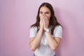 Young hispanic girl standing over pink background laughing and embarrassed giggle covering mouth with hands, gossip and scandal Royalty Free Stock Photo