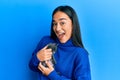 Young hispanic girl with surprised face holding cute cat over isolated blue background Royalty Free Stock Photo