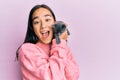 Young hispanic girl with surprised face holding cute cat over isolated pink background Royalty Free Stock Photo